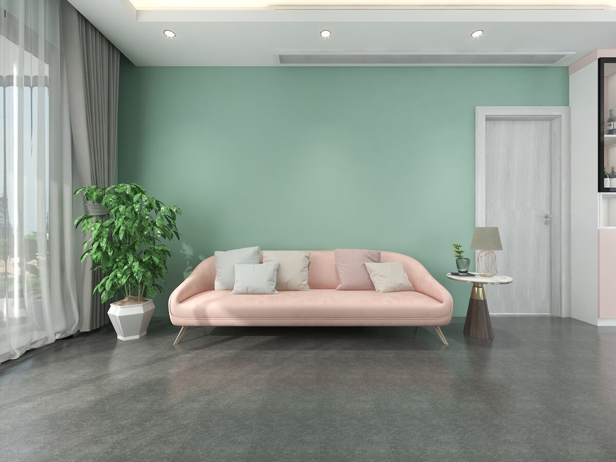 Sala con muro color verde claro, piso gris y sillón rosa claro